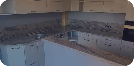 Moderne, weiße Küchenzeile mit grauer Marmorarbeitsplatte, eingebauter Spüle und vielen Schubladen und Schränken.