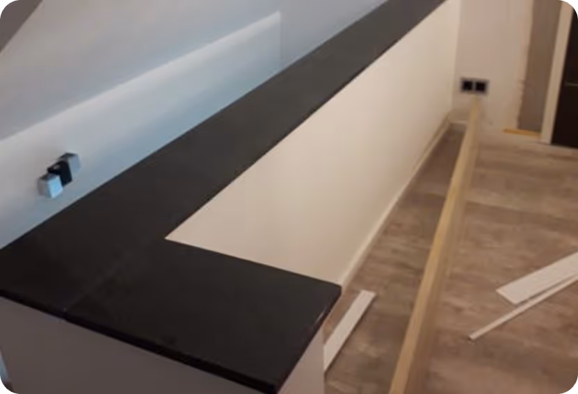 Blick auf eine noch unfertige Treppengeländer-Installation mit schwarzem Handlauf und hellem Holzfußboden.