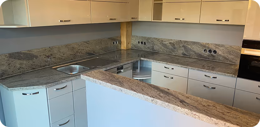 Moderne Küche mit grauen Marmorarbeitsplatten, weißen Schränken und eingebautem Spülbecken.